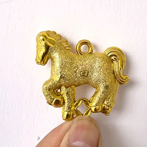 Gros plan d'un pendentif cheval du zodiaque doré avec caractère de chance gravé