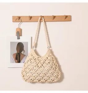 Macro detail of cream macramé hollow woven shoulder bag hanging on a wooden hook hook