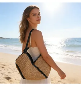 Detailed view of large straw woven beach bag with black trim on a sunny seaside