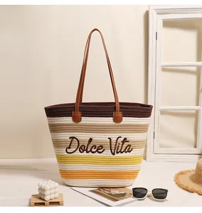 Primo piano di una borsa tote intrecciata a righe con ricamo Dolce Vita per la spiaggia.