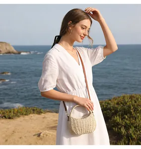 Detail showing a woman in a white dress carrying a small woven straw bag by the sea