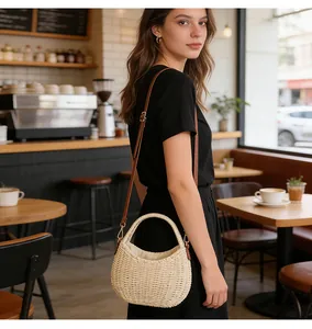 Close-up of a model carrying a stylish woven straw basket bag in a sunlit cafe setting.