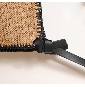Close-up detail of woven texture and black leather strap on straw beach tote bag.