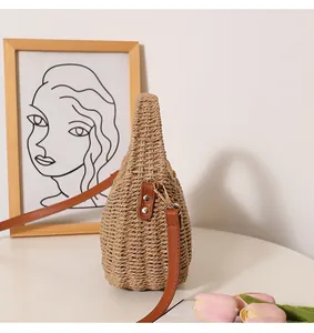 Detail view of a woven straw basket bag with brown leather strap for summer beach