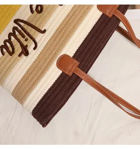 Vista dettagliata di borsa intrecciata in cotone con ricamo e tracolla in pelle marrone