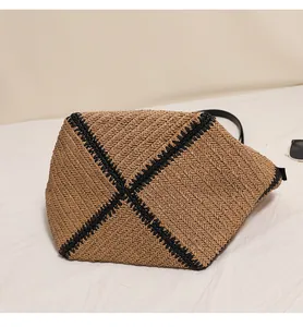 Detail view of the reinforced base on a straw woven tote bag with black contrast trim.