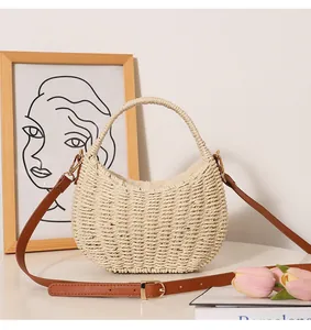 Detailed view of the intricate hand-woven straw texture and the tan faux leather strap.