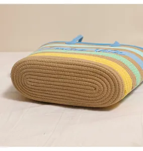 Primo piano della base strutturata e delle strisce colorate di una borsa da spiaggia in cotone.