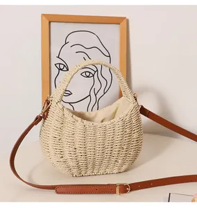 Detailed view of hand-woven straw crescent basket bag with a brown leather strap