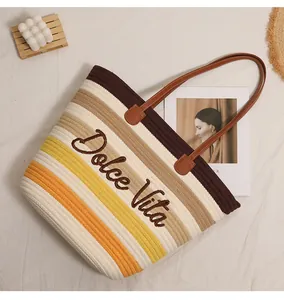Vista dettagliata del ricamo Dolce Vita su una grande borsa da spiaggia intrecciata a righe.