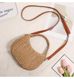 Close-up of hand-woven straw basket bag with adjustable brown leather shoulder strap