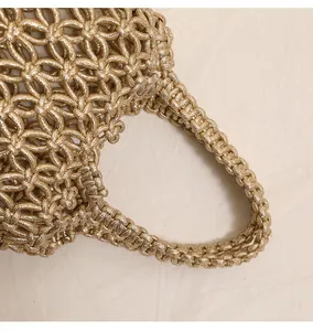 Dettaglio ravvicinato di borsa intrecciata in metallo dorato con manico intrecciato