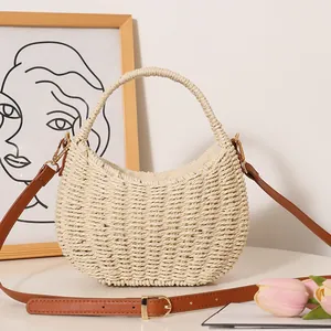 Minimalist cream straw woven basket bag with brown leather strap for beach vacation