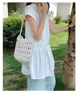 Elegante bolso de cubo de ganchillo blanco hecho a mano en un hermoso jardín soleado.