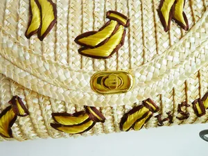 Detailopname van een handgemaakte rieten tas met geel geborduurd bananenpatroon