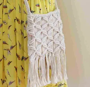 Detailed macro view of cream handmade macrame crossbody bag with long fringes and tassels