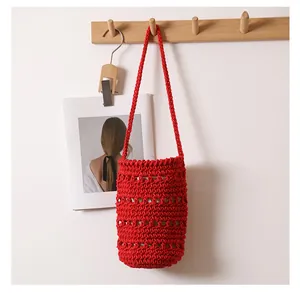 Detalle de un bolso cubo de cuerda de algodón rojo tejido a mano en gancho de madera