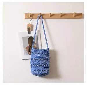 Vista detallada de un bolso de cubo de algodón azul tejido a mano en un soporte.