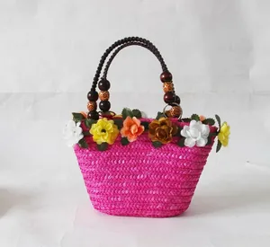 Detailweergave van roze stro strandtas met levendige kunstmatige bloemversieringen