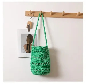 Detalle de bolso cubo verde de cuerda de algodón tejido a mano en soporte