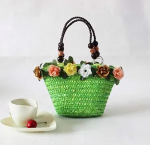 Detailweergave van groene stro geweven strandtas met bloemdecoratie.