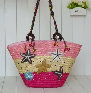 Detailed view of a colorful straw beach bag with star decorations and beaded straps