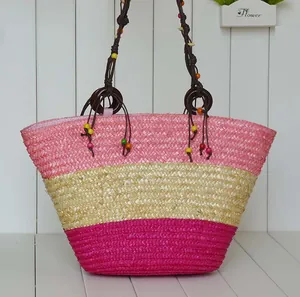 Handmade woven straw beach bag featuring pink stripes and colorful beaded rope handles