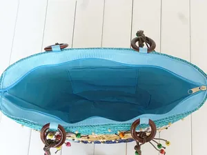 Detailed interior view of a vibrant blue-lined straw beach bag with zipper closure.