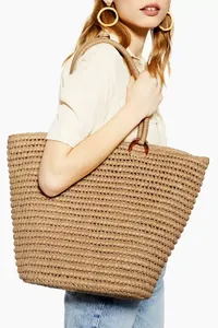 Detalle del bolso playero grande de paja con asas de cuerda y eslabón de anillo.