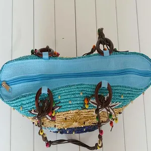 Top view of woven straw beach bag showing blue zipper closure and bead details
