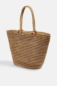 Detalle de bolsa de paja trenzada con elegantes anillas de resina de carey para playa