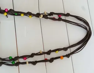 Close-up detail of a brown woven cord strap with colorful wooden beads for beach bags