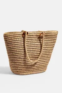 Bolso tote grande de paja tejida con aros de carey para unas vacaciones en la playa.