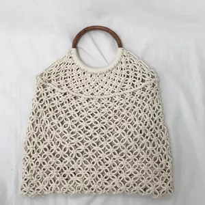 Detalle de bolso de macramé hecho a mano con asas redondas de madera para playa
