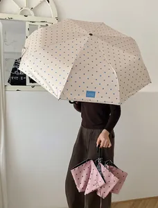 Eleganter beiger Taschenschirm mit Punkten, gebogenem Griff und UV-Schutz-Design
