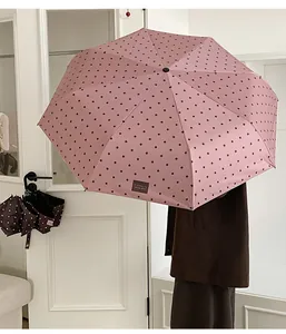 Rosa gepunkteter Regenschirm mit 'it's okay' Label für optimalen Sonne und Regen Schutz