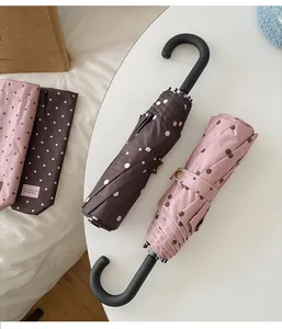 Zwei kompakte faltbare Punkt-Sonnenschirme mit eleganten schwarzen Rundgriffen