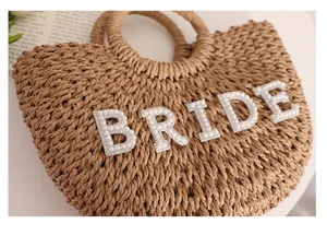 Detalle de un bolso de paja trenzada con una elegante inscripción 'BRIDE' en perlas.