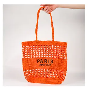 Détail du sac de plage en paille orange ajouré avec broderie de lettres PARIS chic.