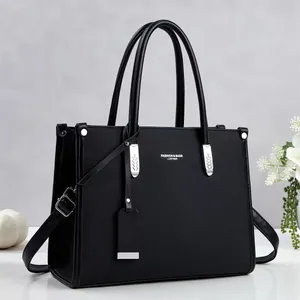 Vista detallada del elegante bolso de mano negro con textura y detalles metálicos plateados