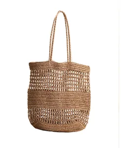 Vue détaillée du tissage ajouré de ce grand sac à bandoulière en paille marron pour la plage