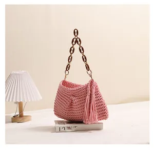 Detail van roze handgehaakte tas met modieuze kwast en schouderband van harsketting.