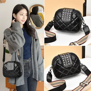 Stylish black quilted crossbody bag featuring silver rivets and wide striped guitar strap