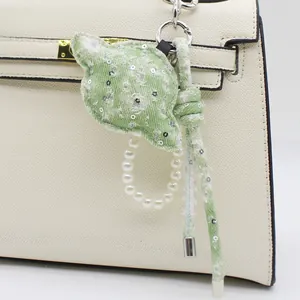 Dettaglio di un ciondolo per borsa a forma di pianeta in denim verde e perle.