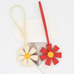 Close-up of cute 3D PU leather flower bag charms in red and cream for fashion bags.