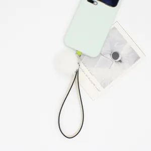 Close-up of white fluffy pom-pom and PU leather lanyard on mint green phone case