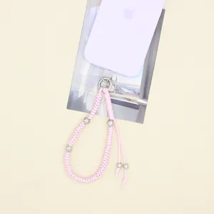 Détail d'un cordon de téléphone tissé à la main en rose avec des perles argentées décoratives