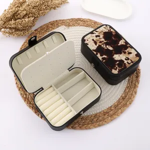 Close-up of portable jewelry box with cow print and multi-functional compartments