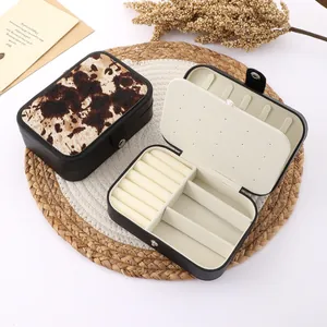 Detail view of retro cow print jewelry box showing internal compartments and ring slots