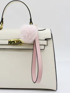 Close-up of a soft pink fur ball bag charm with a pink faux leather loop